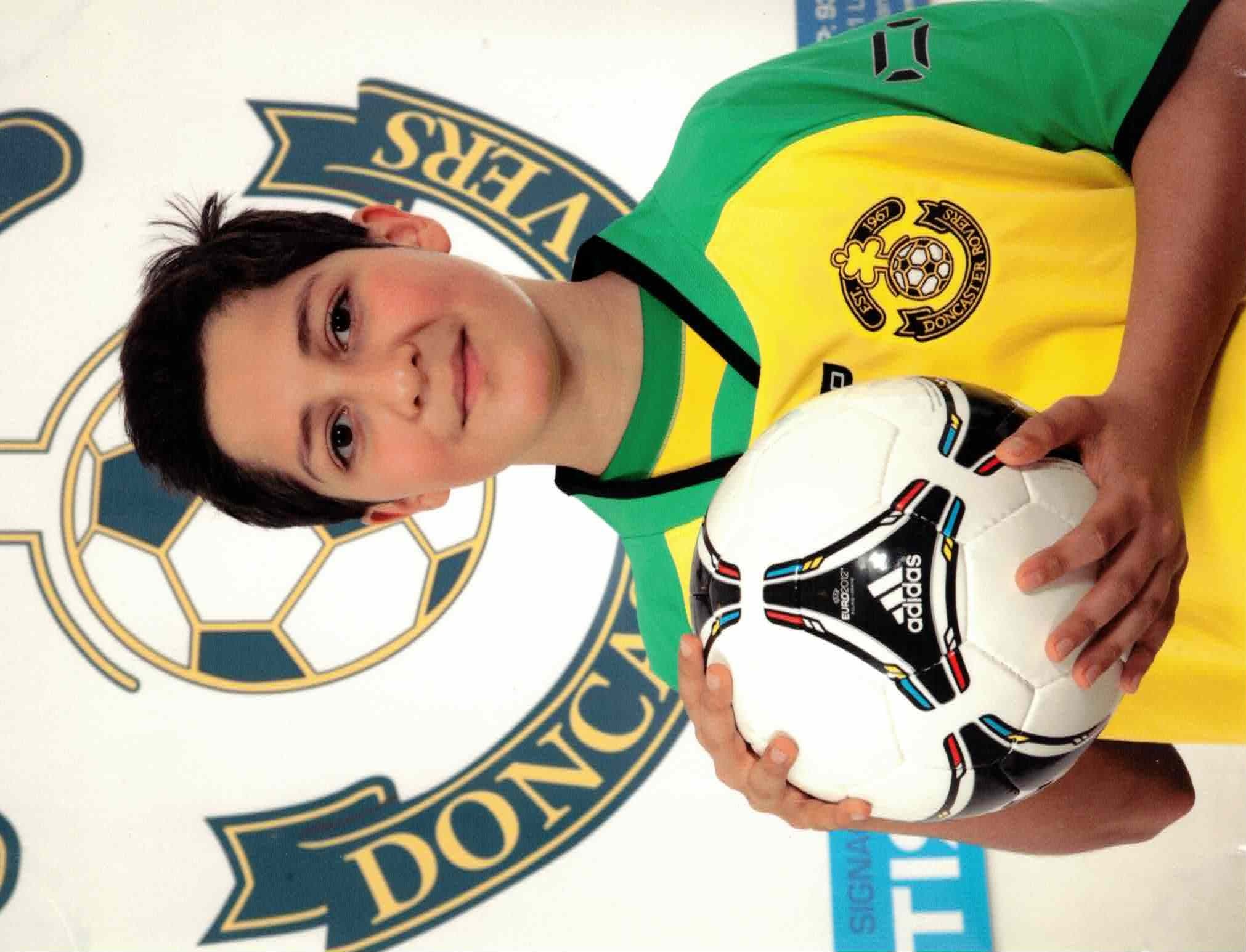 Pedram as a young football player holding a ball